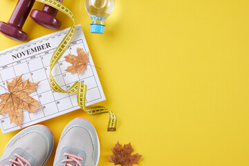 Fall physique makeover journey concept. Top view flat lay of calendar, dumbbells, stylish shoes, plastic water bottle, tape measure, dry maple leaves on yellow background with promo area