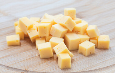 Cubes slices of cheese on a wooden board