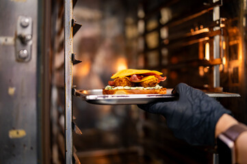 chef hand cooking cheese burger in oven on restaurant kitchen