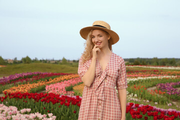 Happy woman in beautiful tulip field outdoors