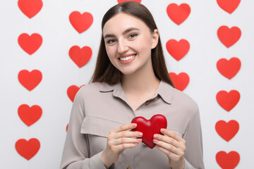 Smiling woman holding red heart on decorated background