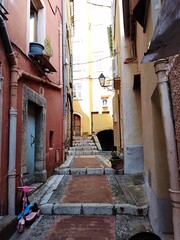 View of a narrow alley and colorful facades of the old Town of Menton, France 