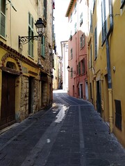 View of a narrow alley and colorful facades of the old Town of Menton, France	