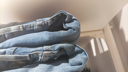 pile of blue denim jeans displayed at white racks, ready to sell in department store of shopping...