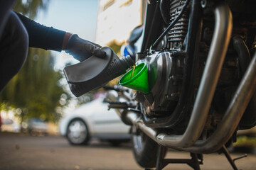 pouring new motor oil into a motorcycle engine - obrazy, fototapety, plakaty