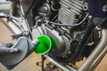 Fototapeta na wymiar pouring new motor oil into a motorcycle engine