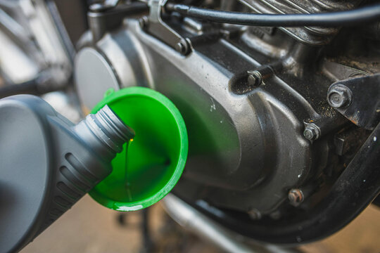 pouring new motor oil into a motorcycle engine