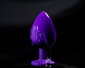 Intimate lubricant pours on a purple anal plug on a black background. Copy space. 