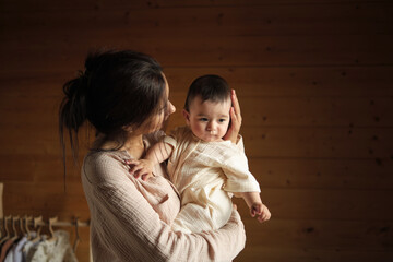 Capturing the Essence of Motherhood: A Radiant Mom Cradles Her One-Year-Old Daughter in Soft, Beige...