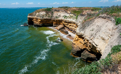 Steep clayey and shell rock shore overgrown with wild steppe vegetation on the island of Berezan,...