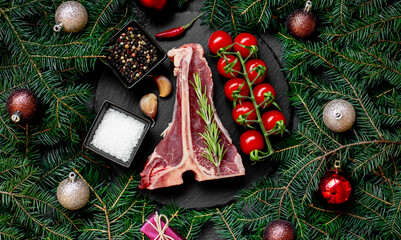 Christmas raw T-bone steak on a background with a fir tree and Christmas toys