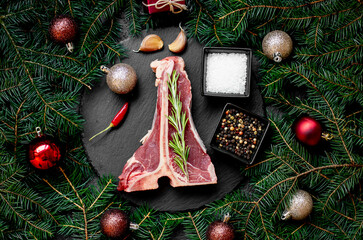 Christmas raw T-bone steak on a background with a fir tree and Christmas toys
