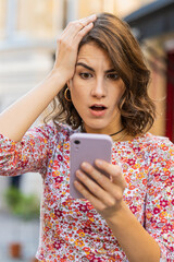 Young woman use smartphone typing browsing, loses becoming surprised sudden lottery results, bad...