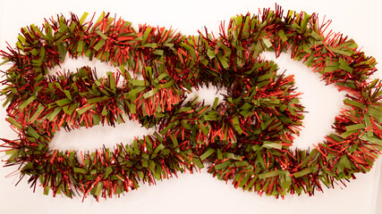 green and red tinsel scattered on white background