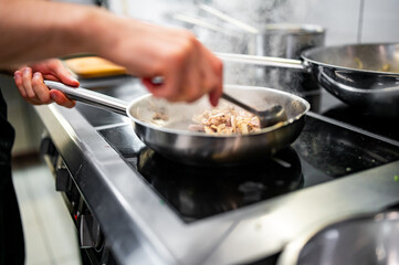 Chef cook hand cooking food in pan at the restaurant kitchen