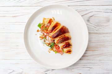 Croissant sandwich with cream cheese and ham on a white plate.