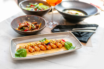 Fried shrimp in creamy sauce with mango and basil on a gray plate