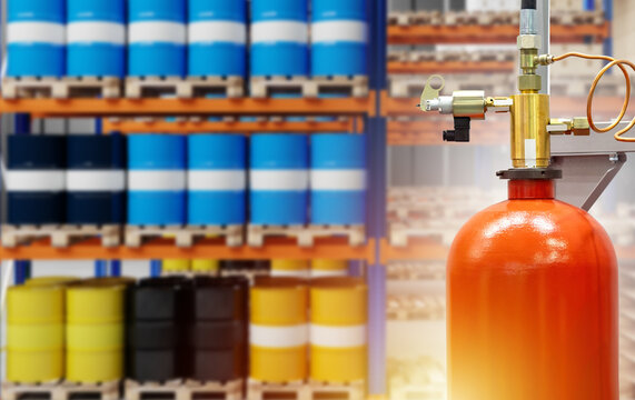 Industrial Fire Extinguisher. Combustion Control System In Warehouse. Red Fire Extinguisher Near Racks With Barrels. Fire Safety Technologies. Equipment To Stop Burning Buildings.