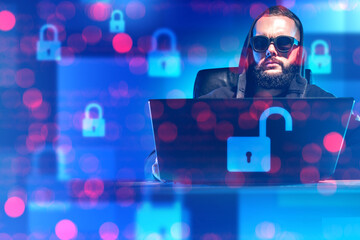 Man hacker. Guy with laptop works in field of cyber security. Hacker cracks passwords. Man in caber hood is criminal. Open locks are metaphor for breaking security. Bearded guy hacker
