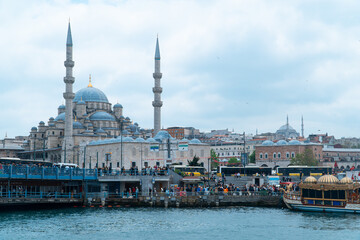 Fototapeta na wymiar Istanbul, Turqey - Mai 23, 2023 : Touristic sightseeing ships in Golden Horn bay of Istanbul and mosque with Sultanahmet district against blue sky and clouds. Istanbul, Turkey during sunny summer day