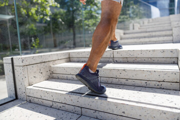 Close up legs and shoes of runner man running with sprint on the stairs in modern city