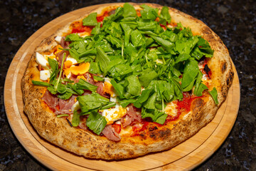 Authentic rustic Italian pizza, "vera pizza", arugula with sun-dried tomatoes and parma ham