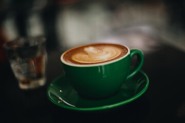 A green cup of hot coffee is placed on the table.