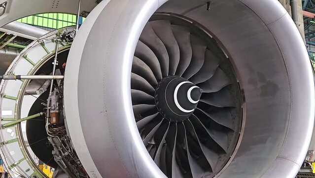 Aviation industry aircraft open engine cover for maintenance and blades of jet turbine rotating by wind.