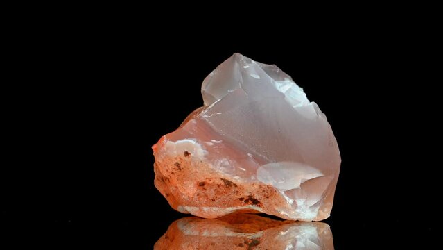 Carnelian (translucent variety of chalcedony - silicon dioxide) sample rotating slowly against a black background.