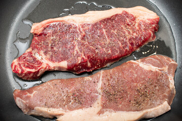 Raw Steaks in spices in a frying pan