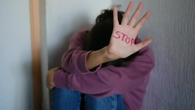 A powerful image depicting the consequences of domestic violence and abuse, showing a woman with visible grazes and beatings on her face, accompanied by the stark word "stop."