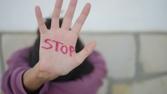 Woman raises her hand with 'stop' written on it. Empowerment, against gender violence, women's rights, and discrimination. Equality, social justice, and gender equity. (March and feminist advocacy)
