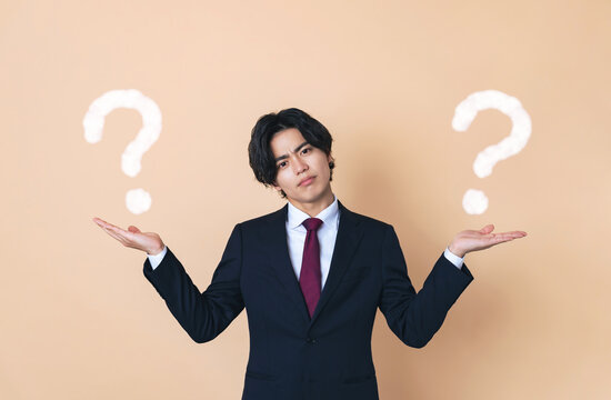 二つのものを比べるスーツを着た若い男性　ビジネスマン