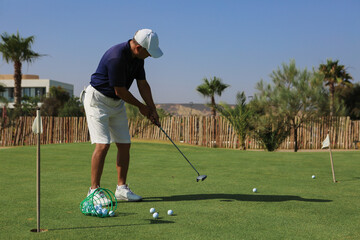 Fototapeta premium Practice Session: Golfer Training with Spilled Golf Balls and Flag