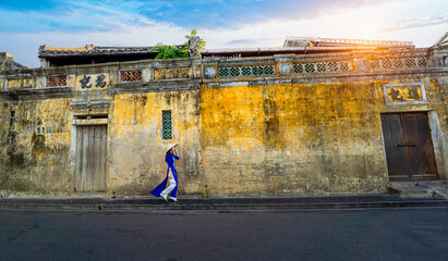 Vietnamese girls in national costumes Walk and lead an ancient bicycle. Play the old town of Hoi...