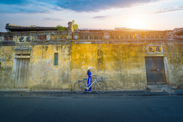 Vietnamese girls in national costumes Walk and lead an ancient bicycle. Play the old town of Hoi...