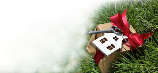 gift with a key and a house on the background of an evergreen tree. winter holidays