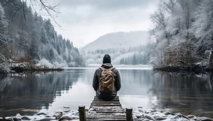Foto op Canvas peaceful alone male man adult traveller sit casual relax on wooden deck at the end of deck with stunning reflecting lake with winter snow cold temperature scenery forest lake background © VERTEX SPACE