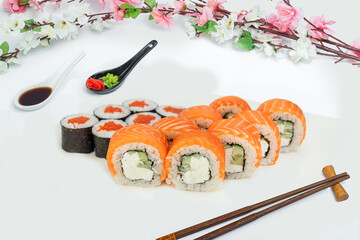 sushi set, a lot of rolls, sakura branch and chopsticks, on a white isolated background © Kurganskiy