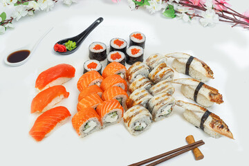 sushi set, a lot of rolls, sakura branch and chopsticks, on a white isolated background © Kurganskiy