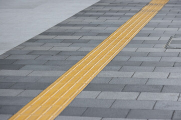 yellow tactile tiles are installed on outdoor pedestrian walkways.