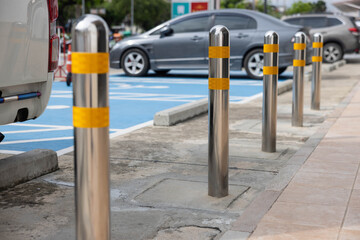 stainless steel bollards on pathway with the disabled parking lots as background. © Rattanachat