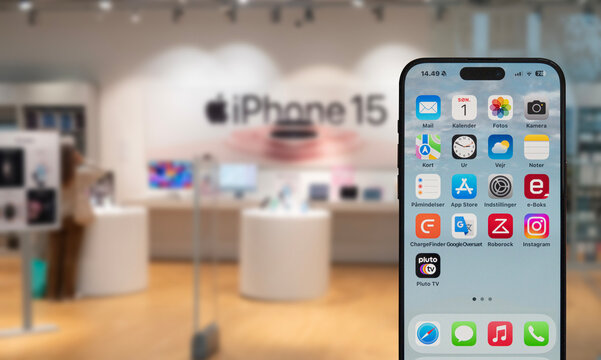 iPhone 15 on display in a store selling Apple products. Blurred shop in background of mobile phone. Copenhagen, Denmark - October 1, 2023.