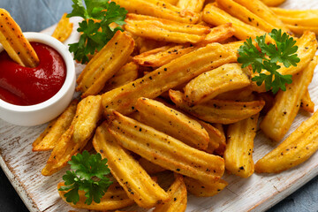 Homemade potato ridge chips, fries with ketchup on white wooden board