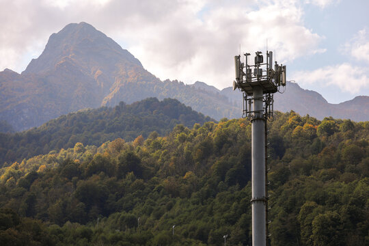 Metal structure, communication tower in a mountainous area, against the background of high mountain peaks. Russia, Krasnaya Polyana, Sochi.