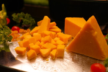 Yellow cheddar cheese is cut into bite-size pieces and plated.