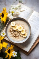  Breakfast or dessert, unsweetened dietetic porridge with hazelnuts and sliced banana in a ceramic bowl on a wooden modern background, book and flowers, top view. Breakfast recipes. Healthy food