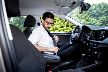 Young handsome businessman driving his car, side view