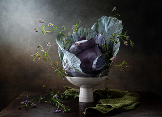 Modern still life with red cabbage and small flowers in a vase on a wooden table
