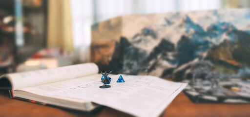 Miniatures and blue dice place on adventure story TTRPG book role playing tabletop game and board...